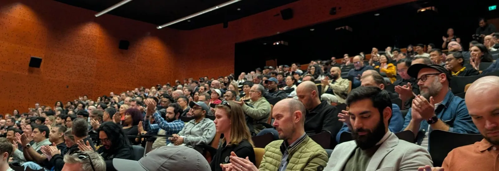 A packed, steeply raked lecture theatre at AUT, with rows of attendees filling the seats before the talks began